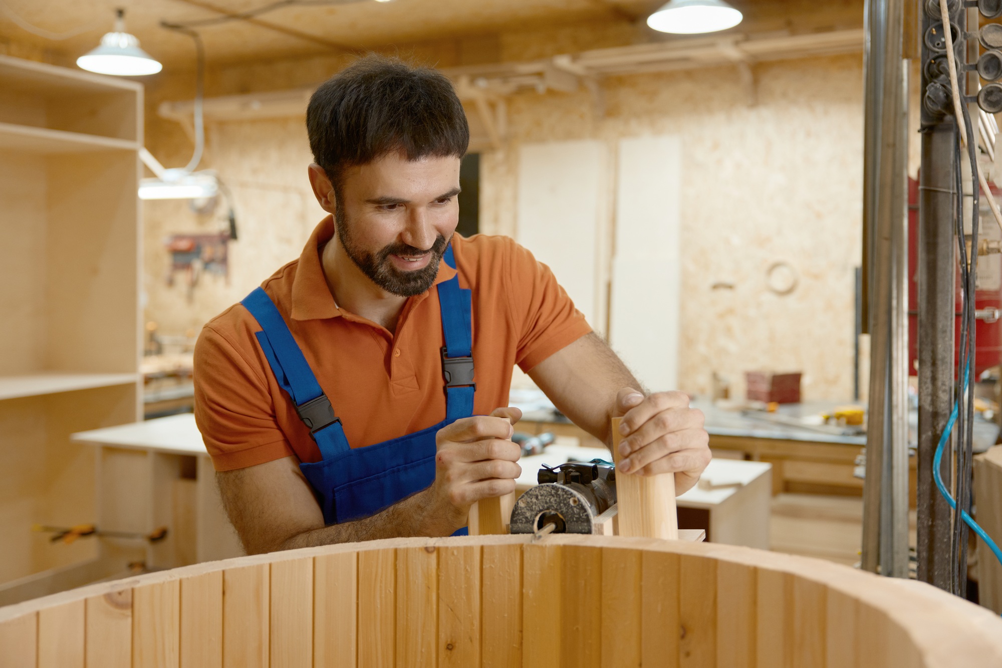 Carpenter working on mini home wooden phytobarrel sauna at workshop